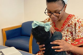 Photo of a Mother holding her child while working on her computer. Photo by Riane Tyler via iPhone 11