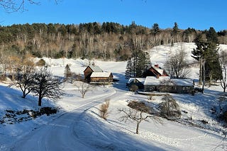 Rural scene in Vermont in winter, with a few houses in the vicinity of a forest