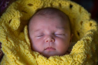 Invincible Summer — a personal photo of the author’s daughter shortly after she was born, wrapped in a yellow blanket.