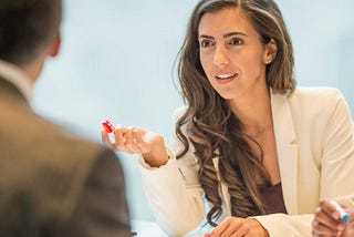 A woman dressed in business professional attire is in negotiations in a meeting room.