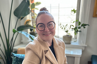 Jen sitting on an armchair with plants in the background