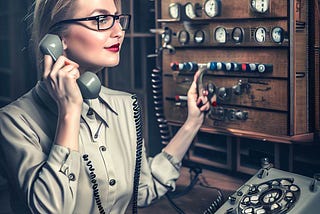 Old-style telephone operator sitting at a switchboard