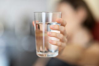 Person holding a clear glass of fresh water.