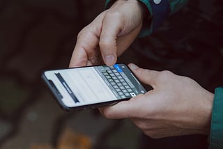 Close up image of hands holding a mobile phone.