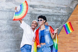 two humans waving PRIDE flags