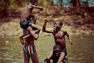 4 boys playing happily in the stream.