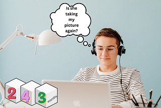 This is an image of a person sitting in front of a laptop wearing headphones and eyeglasses. They have a thoughtful expression, and there is a thought bubble illustration coming from their head with the text “Is she taking my picture again?”. In front of the person, there are illustrated blocks with numbers 2, 4, and 3 on them and the text “months” underneath like an age marker often used to denote the age of a baby in months.