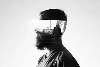 A grayscale side view of a bearded man with an image of someone walking across his head