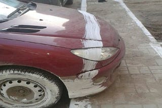 Crosswalk line painted across a car overhaning the paint way.