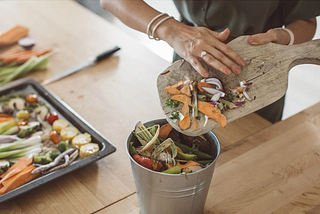 Person scraping food waste into a compost bin