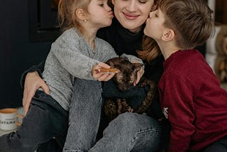 Two children kissing their mother