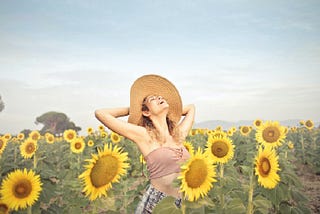 A woman standing on sunflower fields.