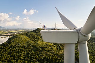 A worker atop a wind turbine performs repairs hundreds of feet off the ground.