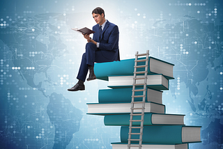 man reading while sitting on a stack of books