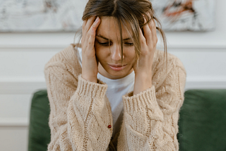 Depressed person sitting on couch with head in hands.