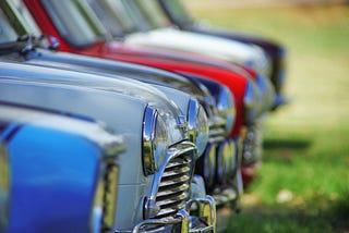 A row of classic cars on a field on a sunny day
