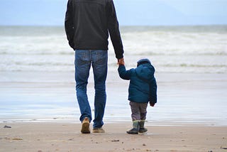 Photo of father with son walking on the beach; posted on Mickey D Markoff 2021 article on gratitude for sons; Photo by Szilvia Basso on Unsplash