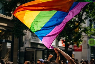 Pride flag being waved with two hands during a parade