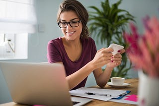 A smiling writer sits in front of her laptop with a sense of achievement.