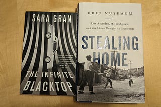 Two books on a table: The Infinite Blacktop by Sara Gran, Stealing Home by Eric Nusbaum