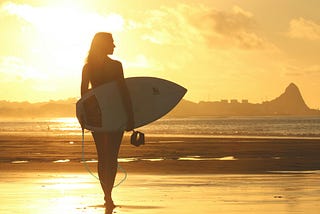 https://www.pexels.com/photo/woman-holding-surf-board-standing-on-shoreline-during-sunset-111085/