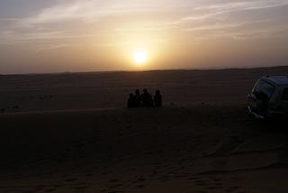 Kelsey’s family sits, facing the sunset in the Middle Eastern desert