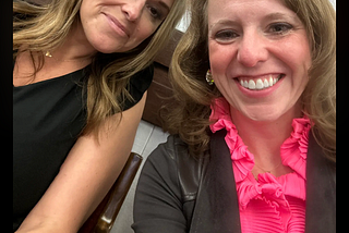 Photo of two women, one wearing a black dress and one wearing a hot pink shirt and brown jacket. Kathryn Harvey, Spartanburg DPC and Amanda McDougald Scott, GCDP watching the SC House Judiciary Committee on the morning of May 9.