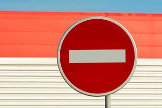 Red and white round sign against a blue, red, and white wall