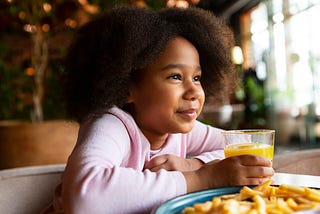 Little Black girl holding glass of orange juice