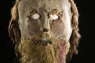 Leather mask with crudely cut and stitched eyeholes; hair is attached to form beard, mustache, and coiffure