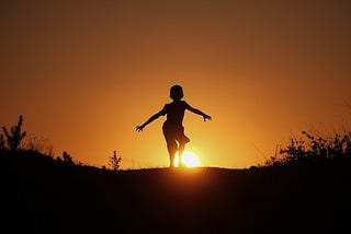 A boy walking into the sunset