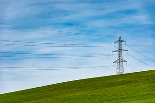 An electrical tower on a grass field.