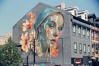 a mural of a beautiful young woman on the side of a building