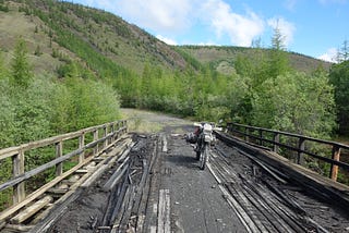 A motorcycle stands on a rotten bridge in the Russian Far East.