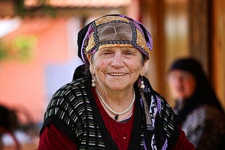 An Eastern European older woman with a head scarf smiles