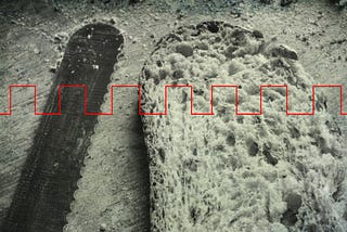 Black and white photo of a bread knife and a piece of cut bread with a red square-tooth wave running across the image