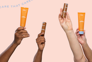 An image showcasing inclusivity, featuring four arms of different shades holding Kleer skincare products. Two arms are fair-skinned, one arm is olive-toned, and one arm is dark-skinned. The products held in the picture are a Kleer jelly cleanser tube and a Vitamin C moisturizer tube. The focus is on the diversity of the arms, indicating that the Kleer skincare line is designed for all skin types and shades. The image promotes inclusivity and celebrates diversity