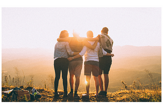 Four friends standing together looking at a sunset