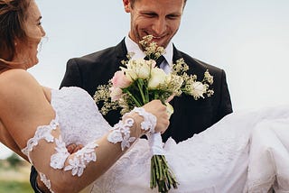 Happy couple on their wedding day, woman in white wedding dress, husband and wife smiling.