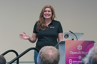 Discover employee Lise Noble wears a black Discover shirt and stands in front of a group of people speaking on the role of design in open source, at the annual NA Open Source Summit in Vancouver