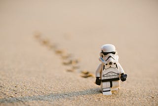 Lego Stormtrooper leaving tracks in the sand.