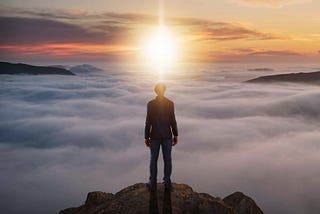 Person in tranquil nature setting on a mountain with sunrise, symbolizing personal growth and intention setting for mental and spiritual health in 2024