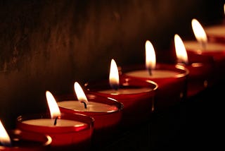 Image of several tea light candles lit in the darkness.