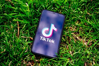 An iphone lying in the grass opened to TikTok