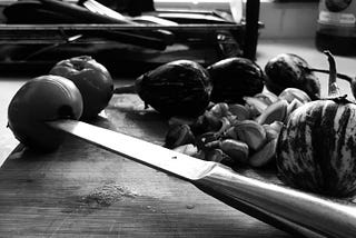 A Knife piercing vegetables on the chopping board