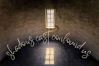 A long rectangular window reflected on the floor of a darkened, curved room. The words, ‘shadows cast confound us’ form a arc in the centre of the image.