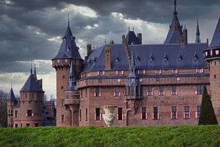 A large brick Tudor castle with stormy skies in the background.