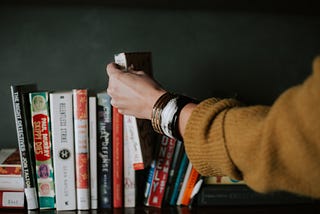 a picture of someone picking up a book from a row of books