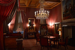 a grand living room heavily draped and decorated with expensive items