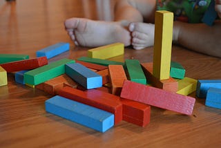 Colorful wooden blocks on floor, with baby feet in background